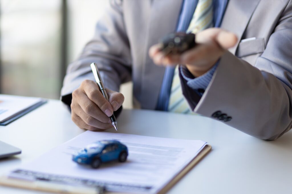 Businessman signing car purchase, lease contract agreement with car salesman, car insurance.
